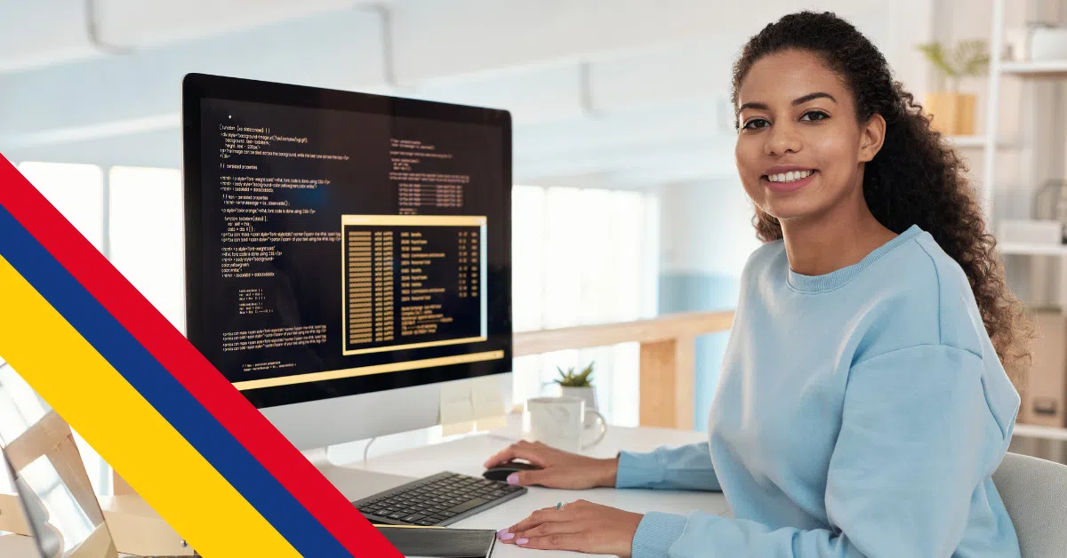 Smiling Colombian software developer coding on desktop computer in modern office.