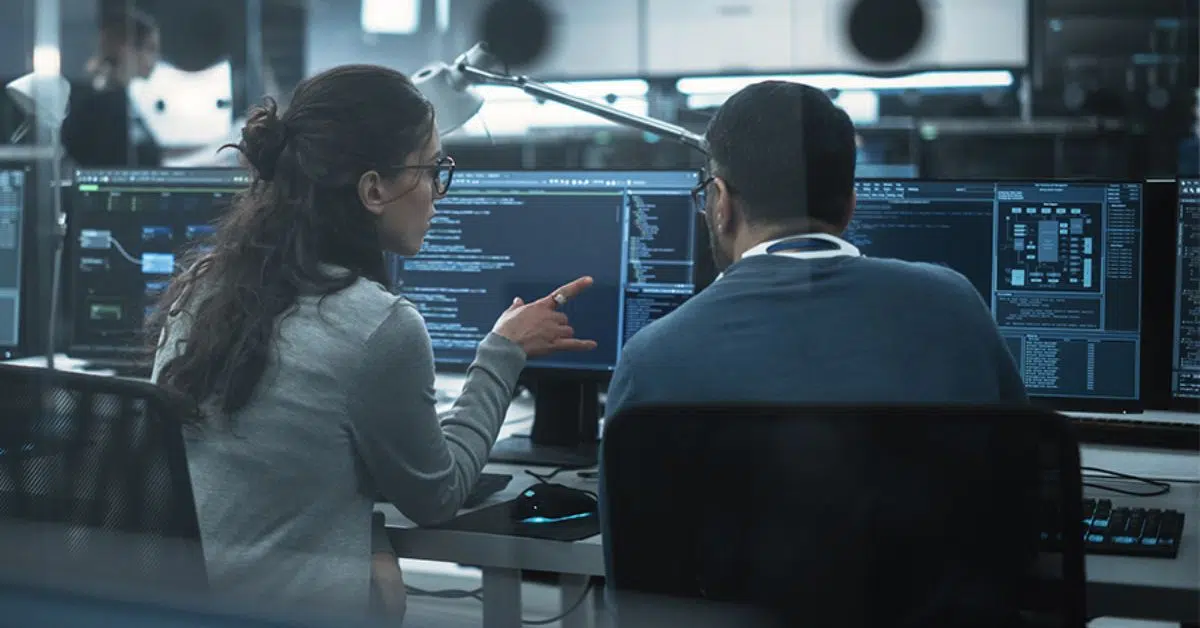Two software engineers discussing AI code and solutions in a high-tech office environment.